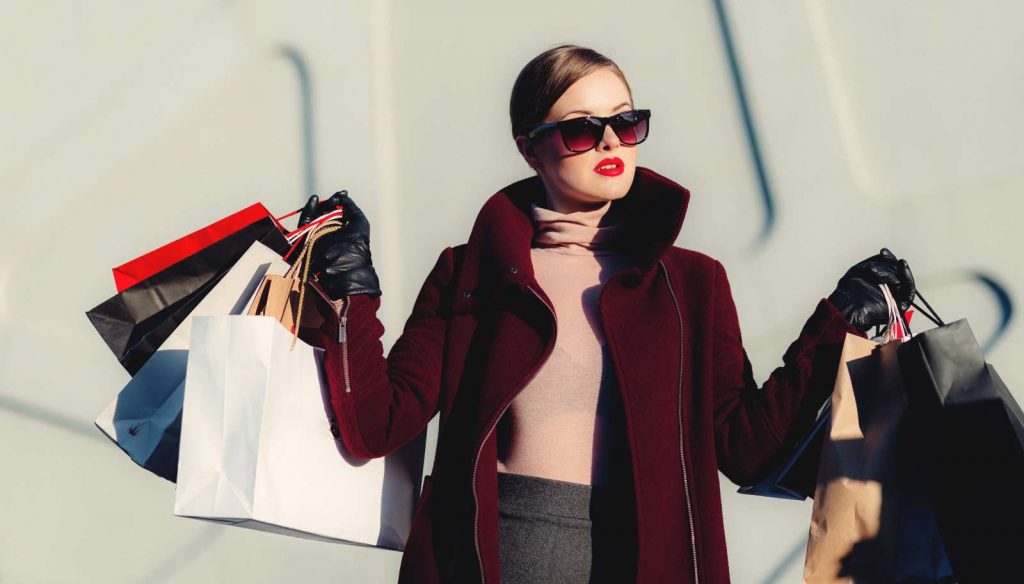 Eine gestylte Frau mit Einkaufstaschen links und rechts